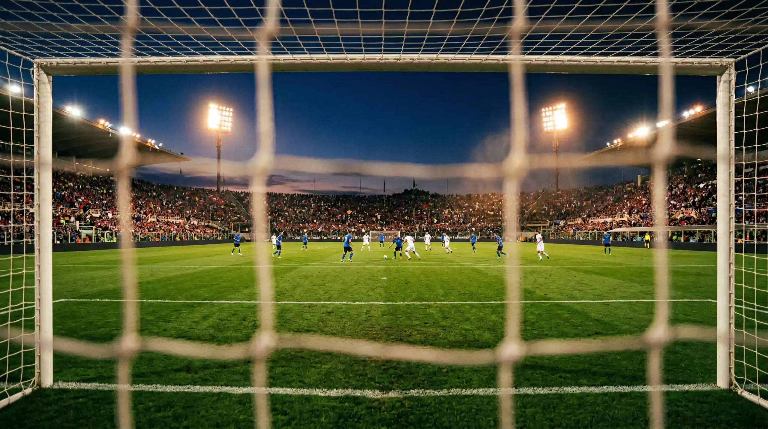 Veduta panoramica di uno stadio di Serie B illuminato di sera con il pubblico sugli spalti